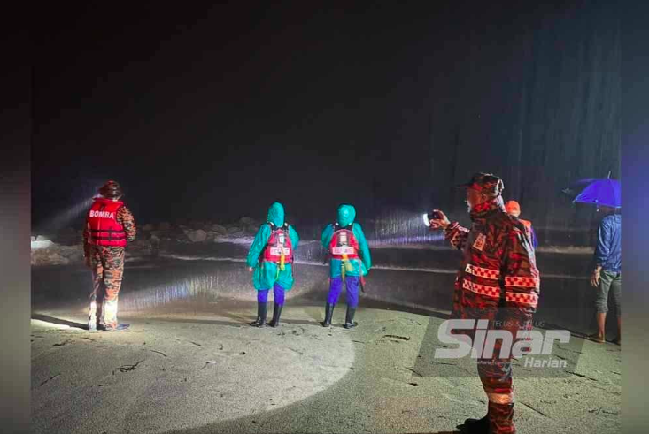 Pihak bomba dan APM menyuluh ke arah batu tempat mangsa dipercayai hilang. Foto Sinar Harian - ADILA SHARINNI WAHID